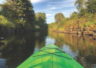 front of a bright green kayak paddling into a bay